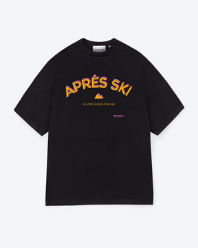 Ein schwarzes T-Shirt mit einem orange, rosanen Print auf der Vorderseite der aus dem Schriftzug "APRÉS SKI IS VERY GOOD FOR ME" besteht und aus einem kleinen Berg in der Mitte, welcher ebenfalls orange, rosa ist. 