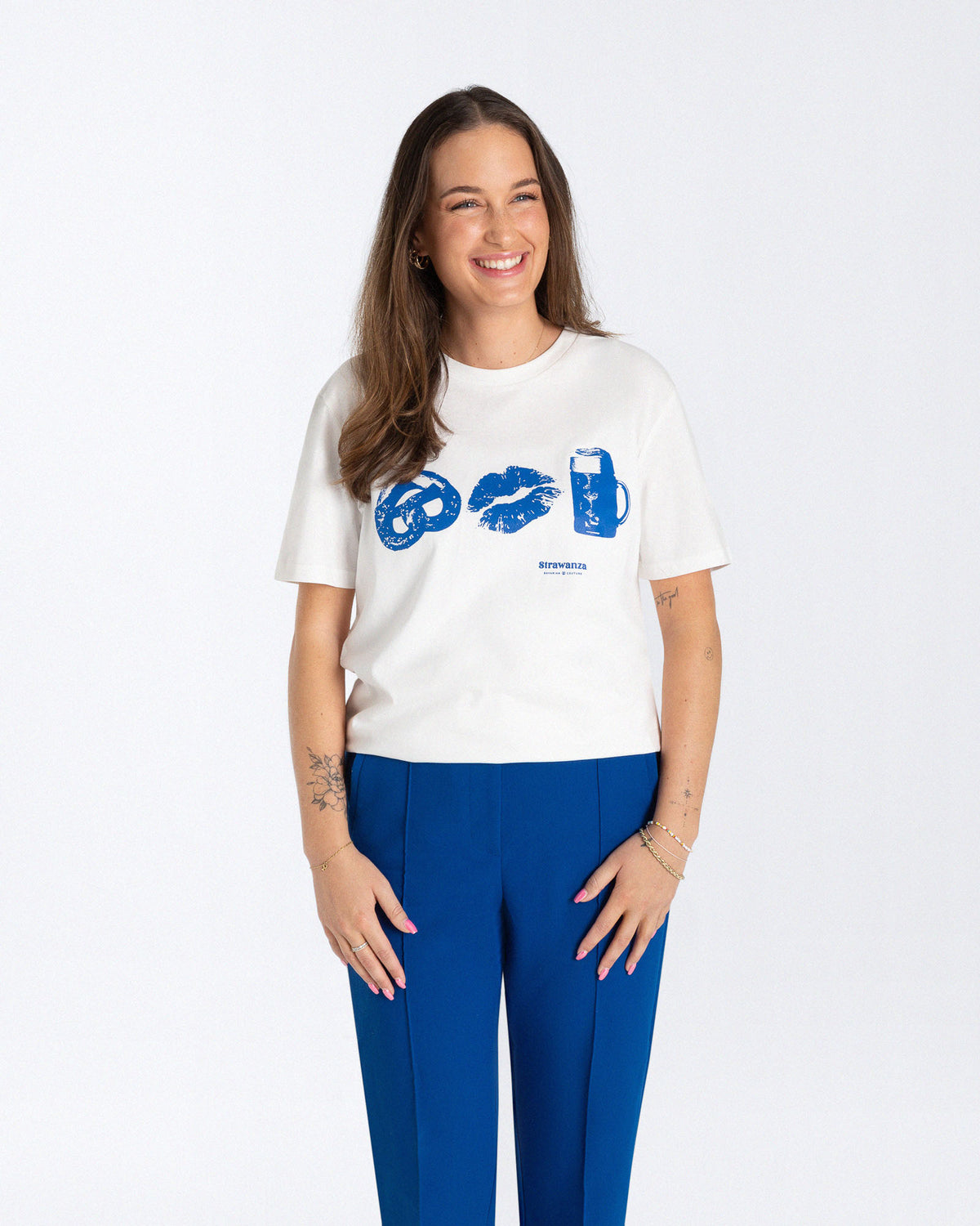 Ein weibliches Model trägt ein weißes T-Shirt mit einem großen, blauen Motiv vorne auf der Brust, zu erkennen sind eine Breze, ein Kussmund und Bier. 