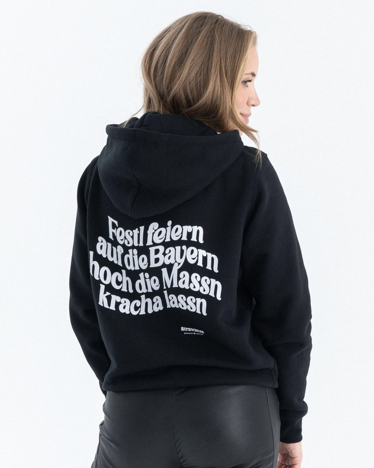 Entdecken Sie den stylischen 'FEIERN BAYERN HOODIE' von Strawanza, ideal für Party-Abenteuer. Das Model präsentiert diesen trendigen schwarzen Hoodie im Fotostudio. Der Hoodie zeichnet sich durch sein starkes schwarz und den Siebdruck im Retro Stil aus. Perfekt für Berg- und Partyabenteuer. Hier die Rückseite des Hoodies zu sehen