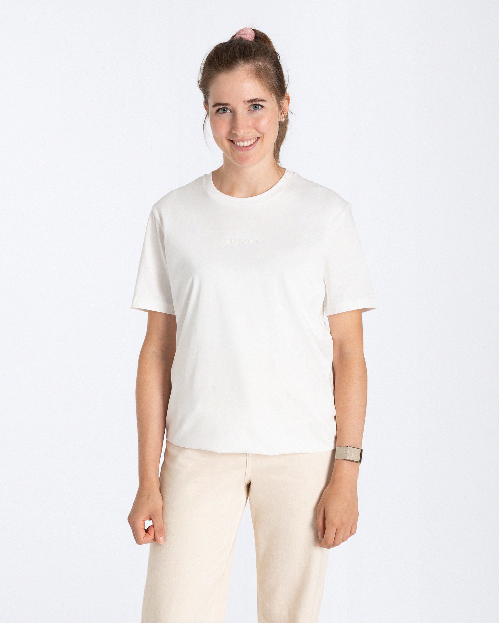 Ein weibliches Model trägt ein weißes T-Shirt mit einem Ton in Ton "Strawanza"  Schriftzug als Stick auf der Vorderseite. 