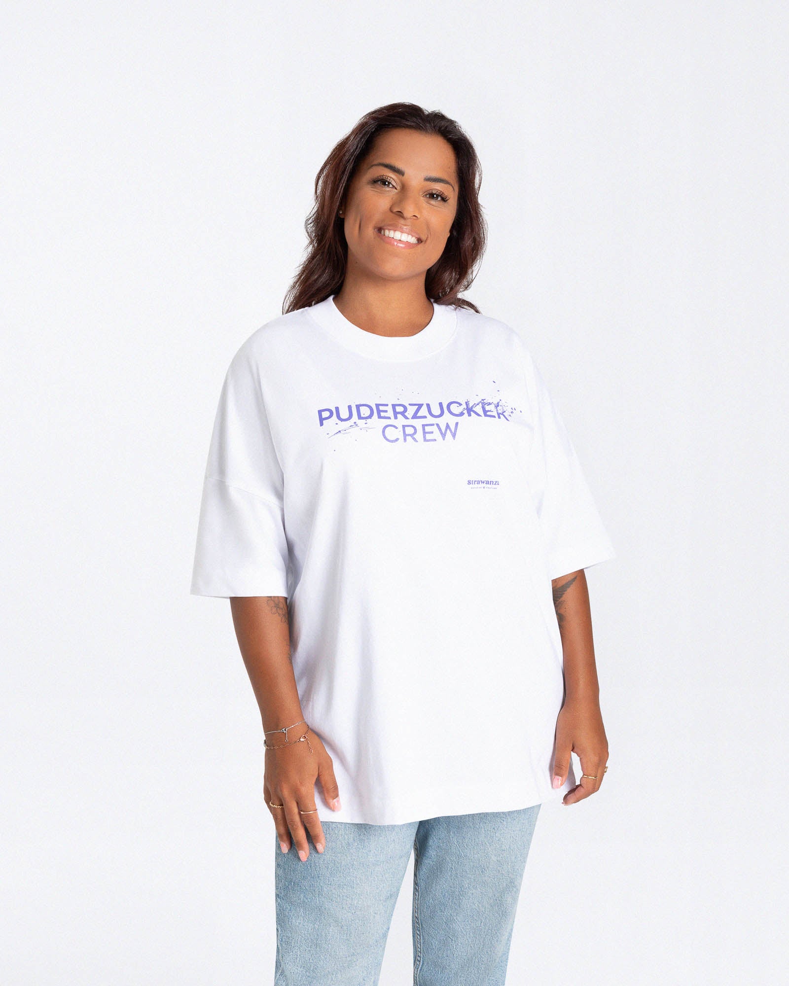 Ein weibliches Model trägt ein weißes T-Shirt mit einem Motiv auf der Vorderseite welches aus einem lilanen Schriftzug besteht welcher 