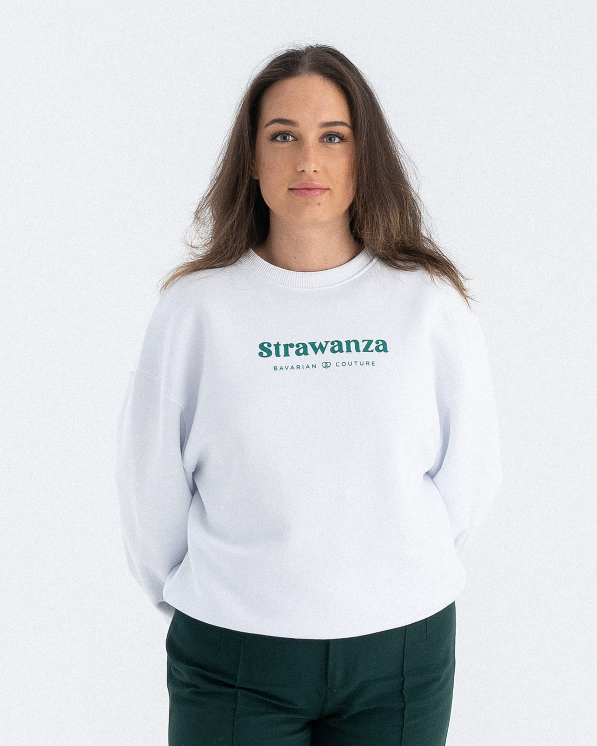 Ein weibliches Model trägt einen weißen Sweater mit einem grünen "Strawanza" und "BAVARIAN COUTURE" Schriftzug auf der Brust.