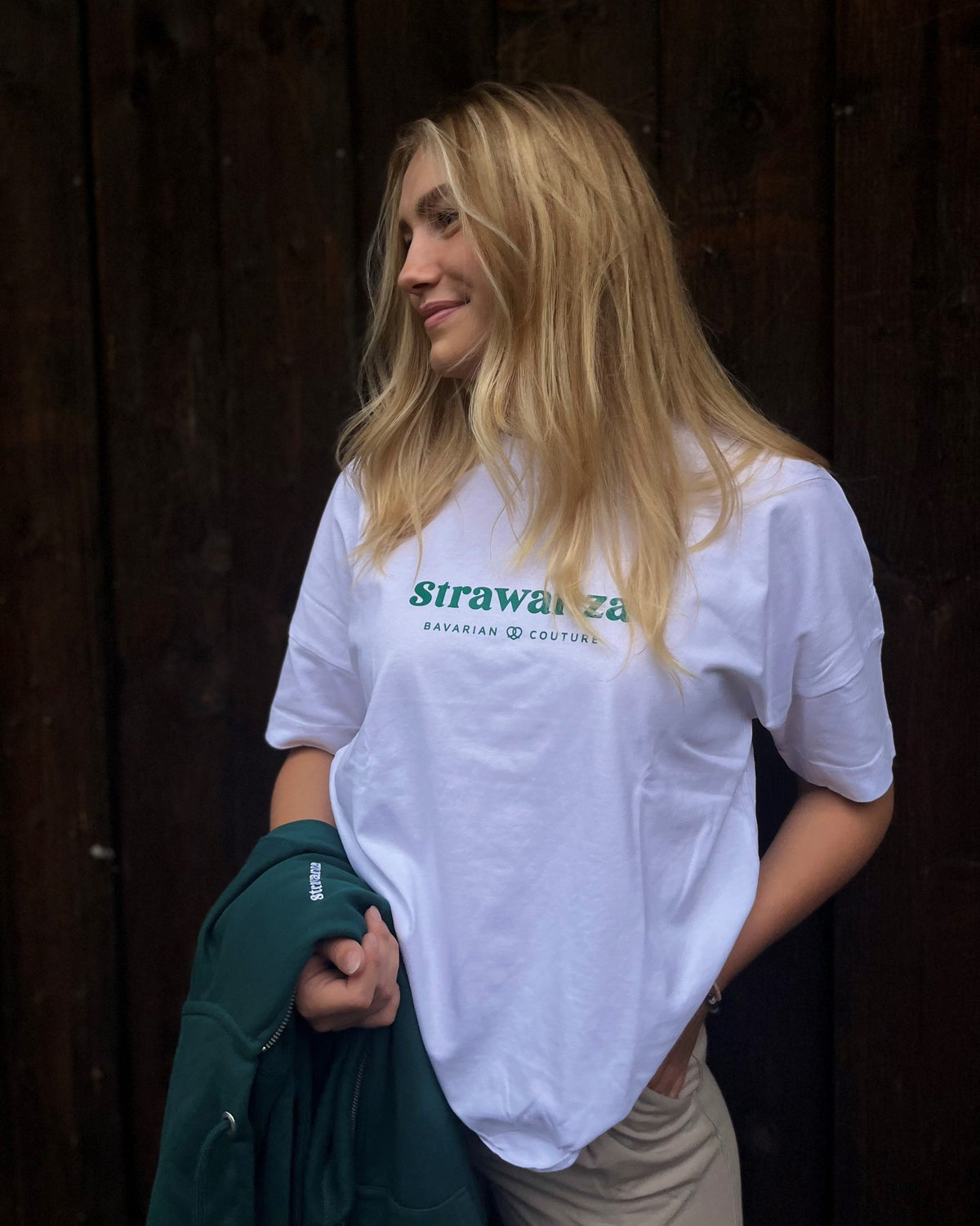 Eine Frau trägt ein weißes T-Shirt mit einem grünem Schriftzug vorne auf der Brust.