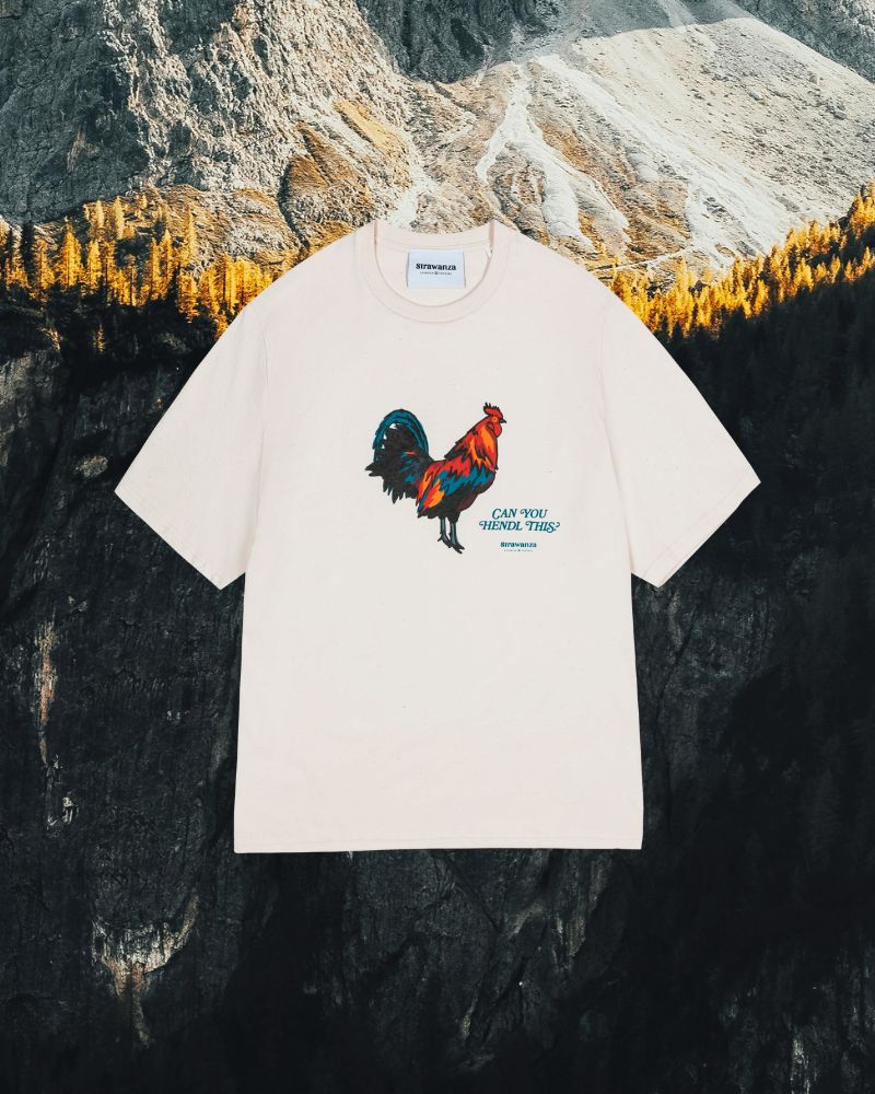 Das "Can you Hendl this" T-Shirt von der Modemarke Strawanza. Plakativ präsentiert vor einer Berglandschaft.