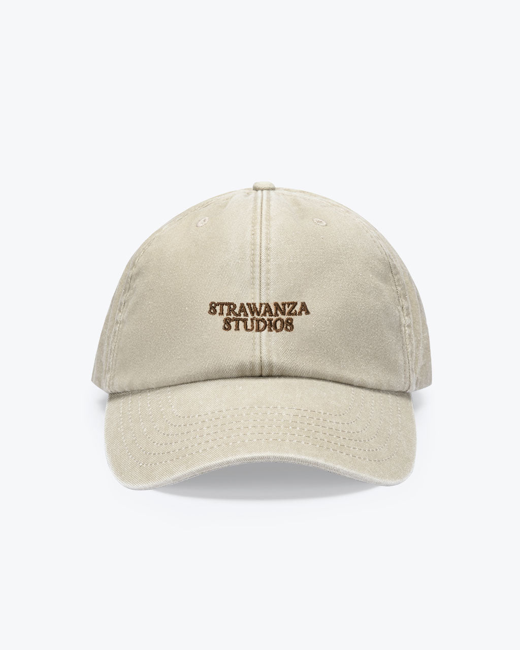 Eine bayerische Cap in der Farbe Sand welches einen braun, bestickten "STRAWANZA STUDIOS" Schriftzug vorne als Motiv hat.