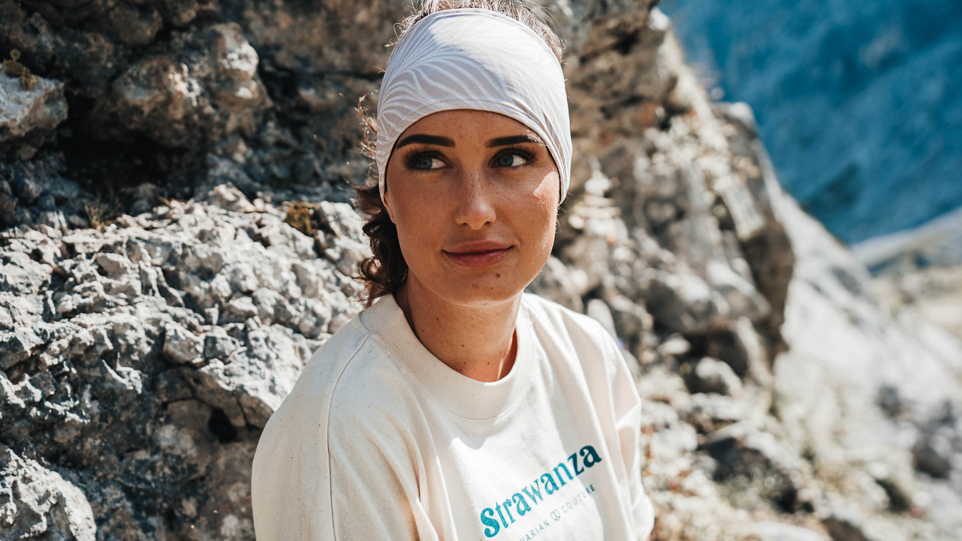 Junge Frau in einer Bergkulisse mit sportlichem Stirnband der Modemarke Strawanza.