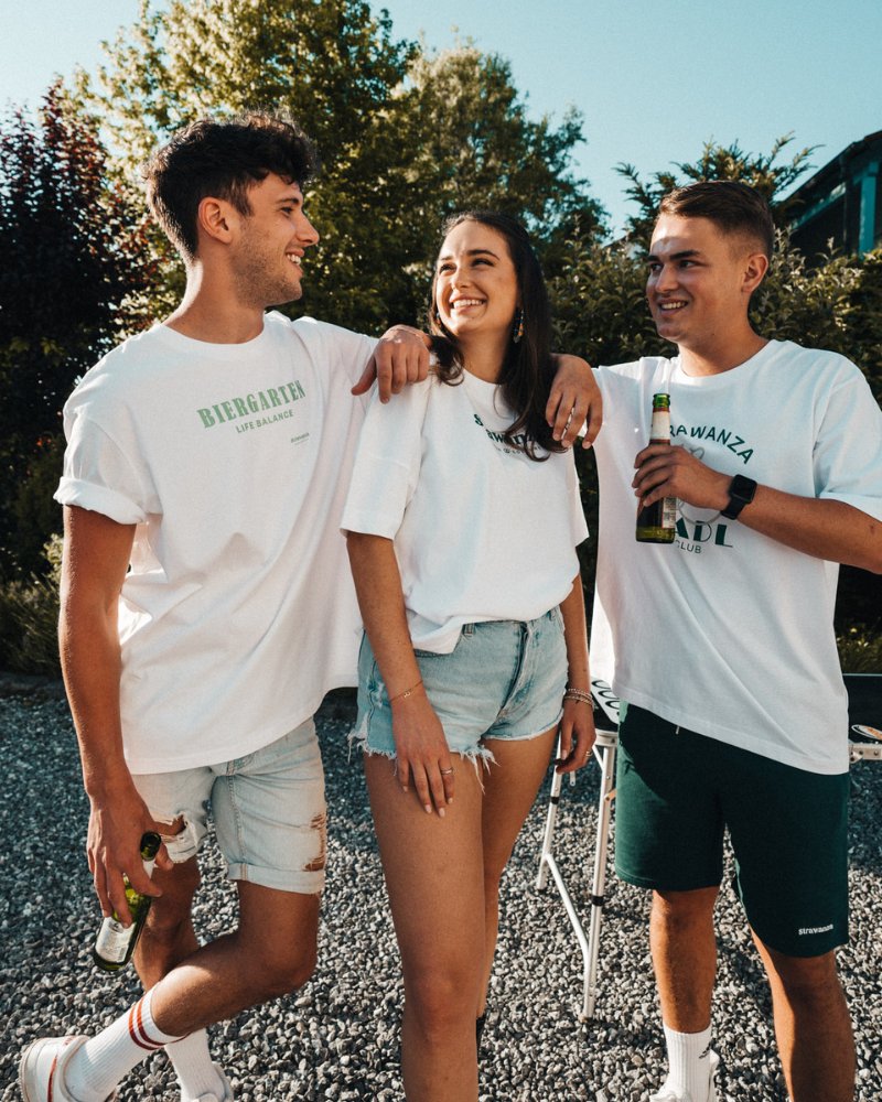 Zwei junge Frauen stehen in Bayern in einer Biergarten Umgebung und präsentieren die neuen Spritz T-Shirts mit Zitronenmotiv von der Modemarke Strawanza Bavarian Couture.