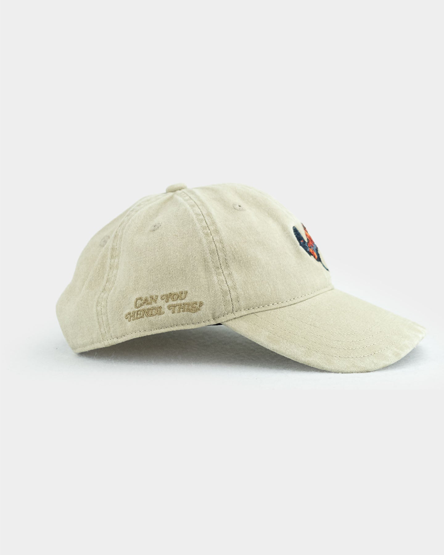 Eine bayerische Cap in der Farbe beige mit einem Hendl als Motiv auf der Vorderseite und einem dunkleren beigen 