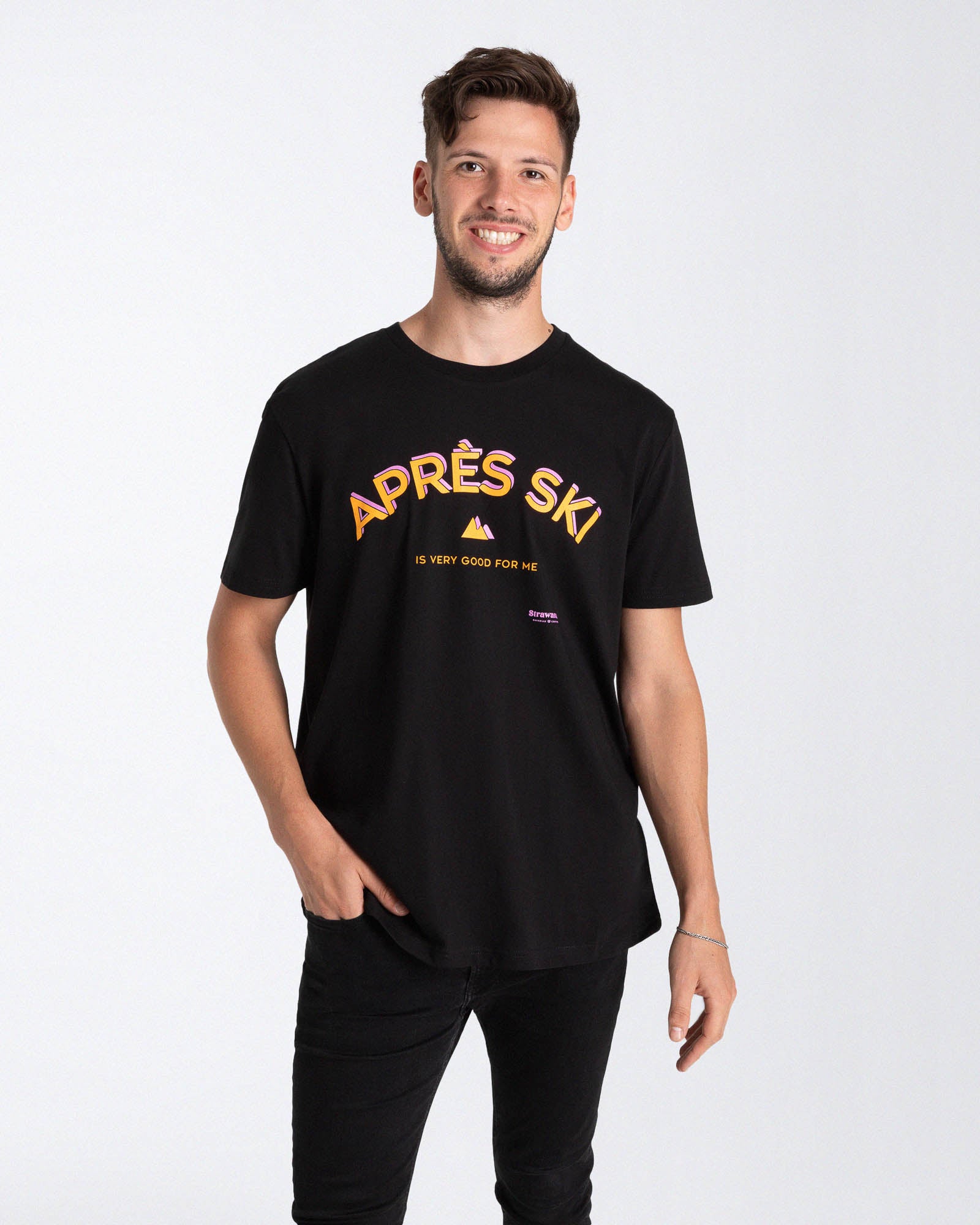 Ein männliches Model trägt ein schwarzes T-Shirt mit einem orange, rosa "APRÈS SKI IS VERY GOOD FOR ME" Schriftzug besteht und einem kleinen Berg in der Mitte der Brust.
