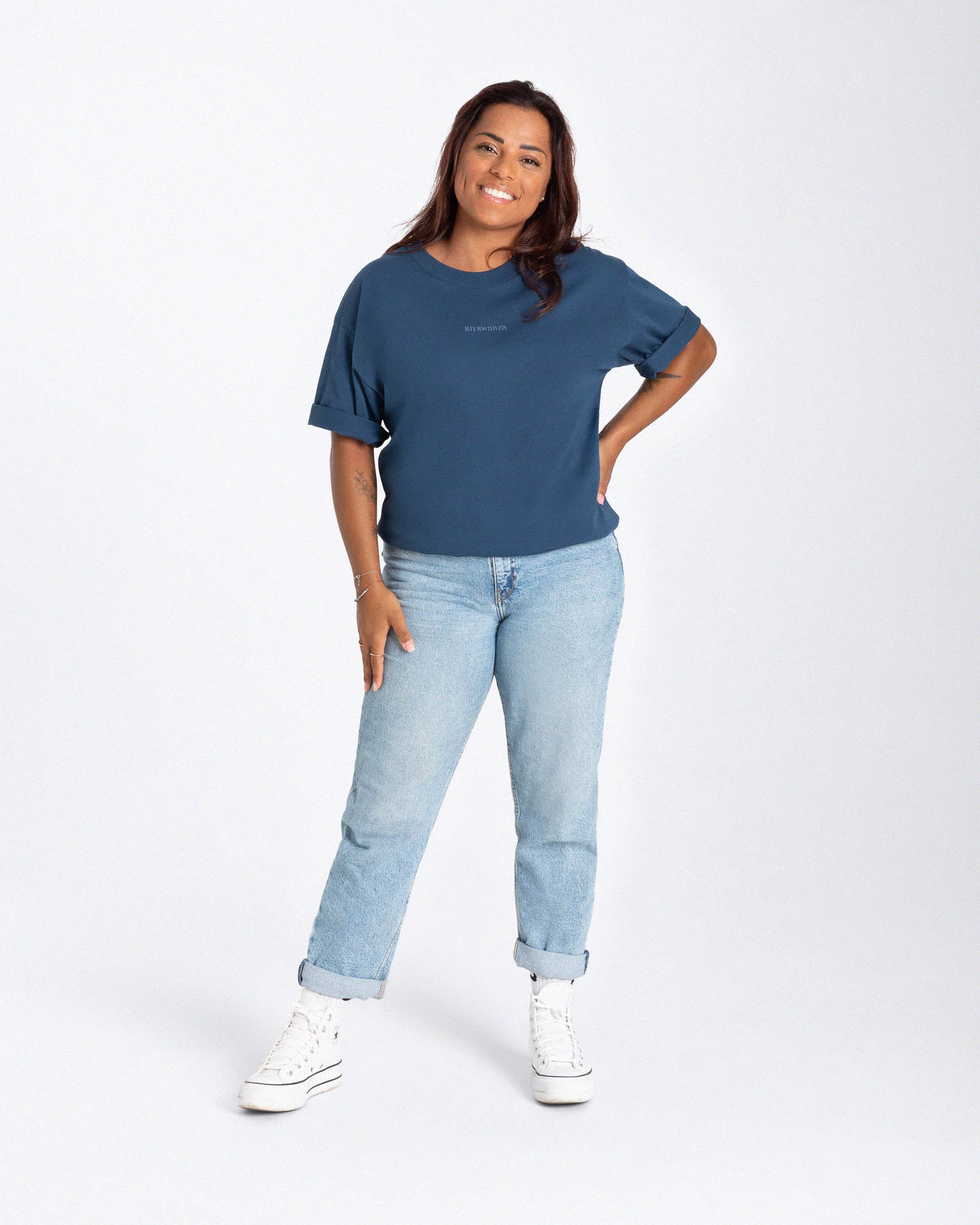 Eine Frau trägt ein blaues T-Shirt mit einem besticktem "Strawanza" auf der Höhe der Brust.