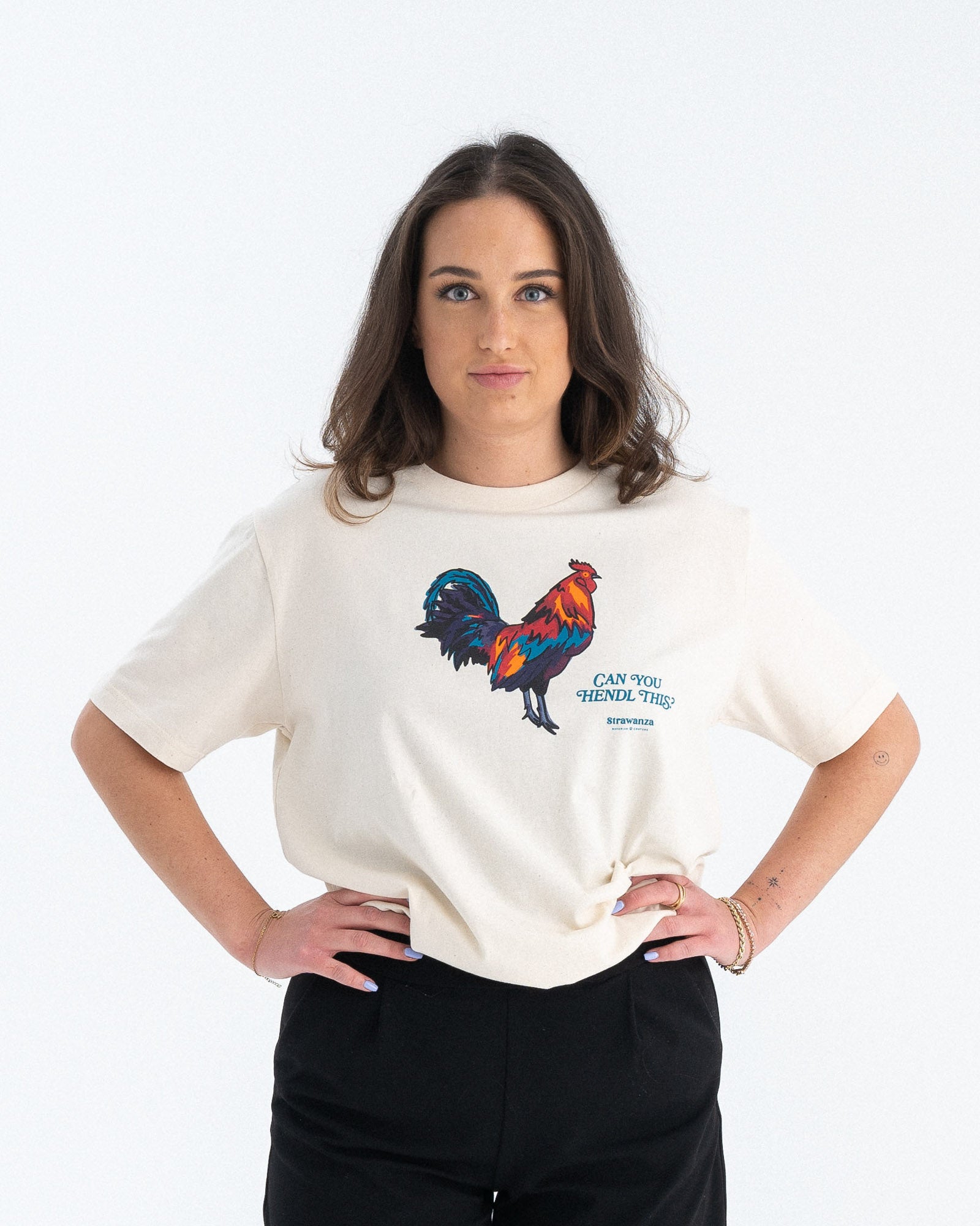 Entdecken Sie das stylische 'CAN YOU HENDL THIS T-SHIRT' von Strawanza, ideal für Party-Abenteuer. Das Model präsentiert dieses trendige beige T-Shirt im Fotostudio. Das T-Shirt zeichnet sich durch sein starkes Motiv  und den Siebdruck im Retro Stil aus. Perfekt für Berg- und Partyabenteuer und Hühnerliebhaber. Hier an einer Frau zu sehen