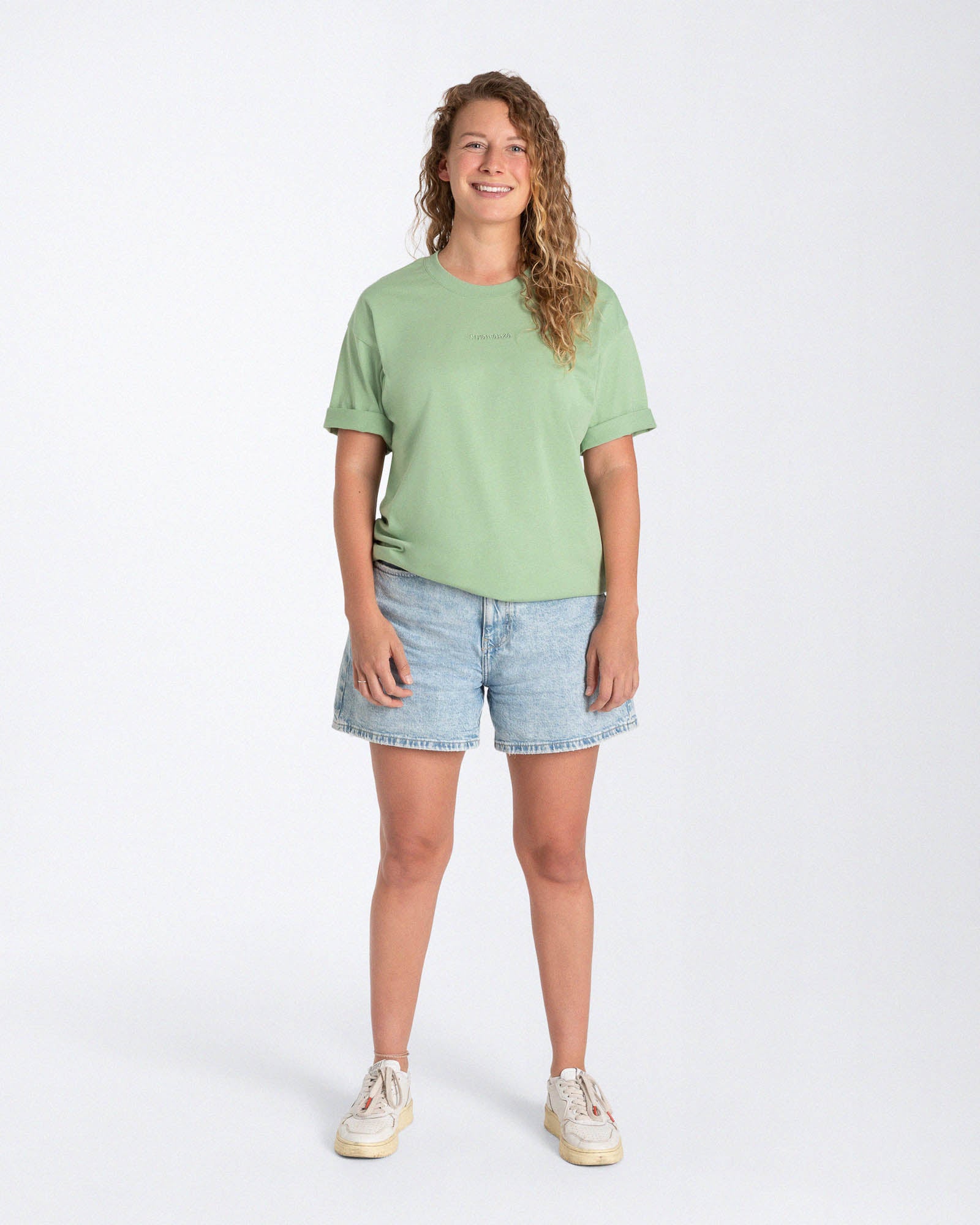 Eine Frau trägt ein hellgrünes T-Shirt mit einem ebenso hellgrünen Wort auf der Brust.