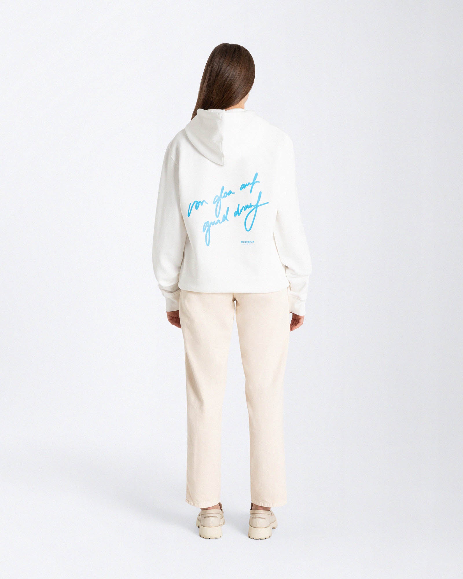 Ein weibliches Model trägt einen vintage weißen Hoodie mit einem hellblauen "von gloa auf guad drauf" Schriftzug als Backprint. 