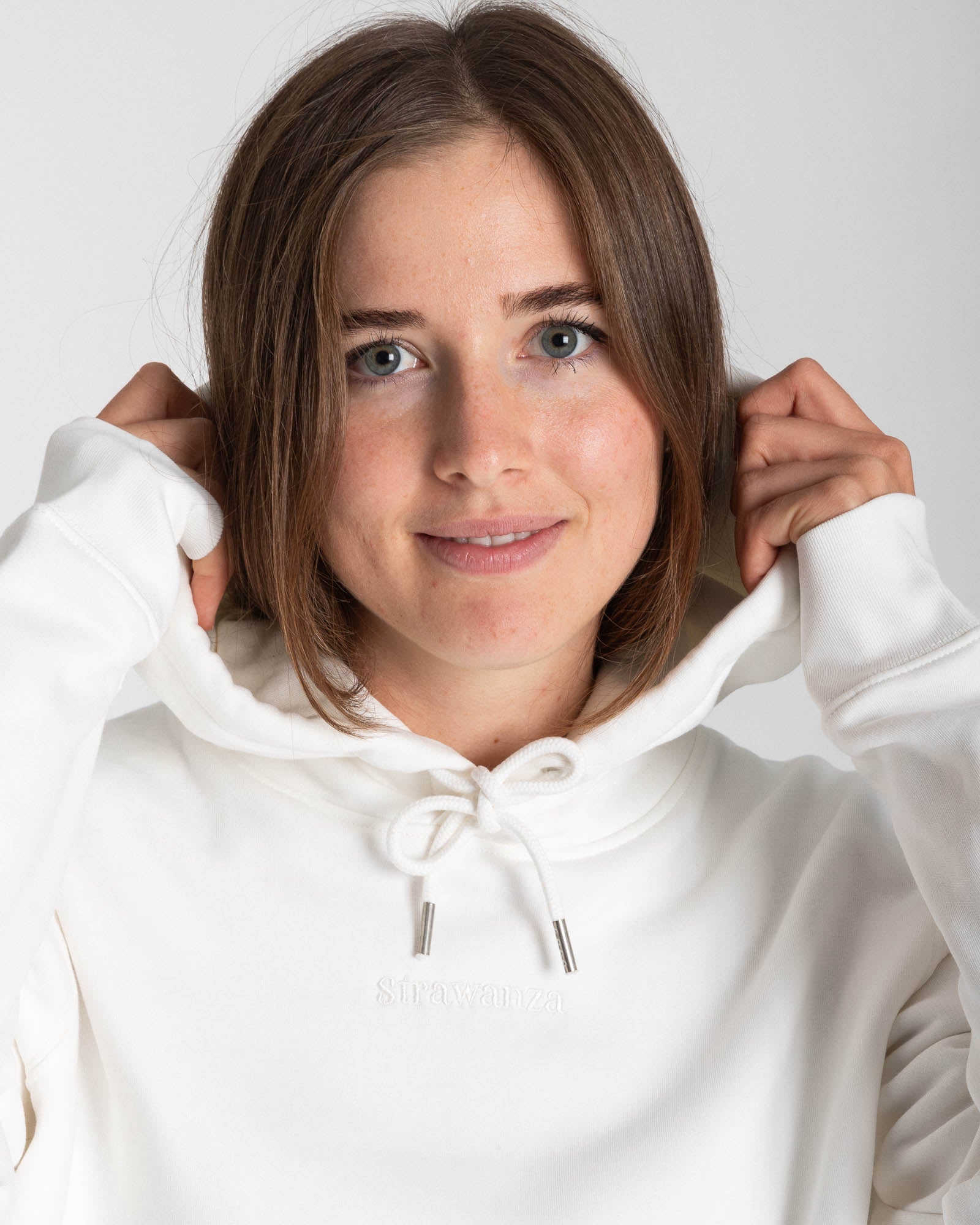 Ein weibliche Model trägt einen vintage weißen Hoodie mit einem in Ton bestickten "Strawanza" Schriftzug auf der Höhe der Brust.