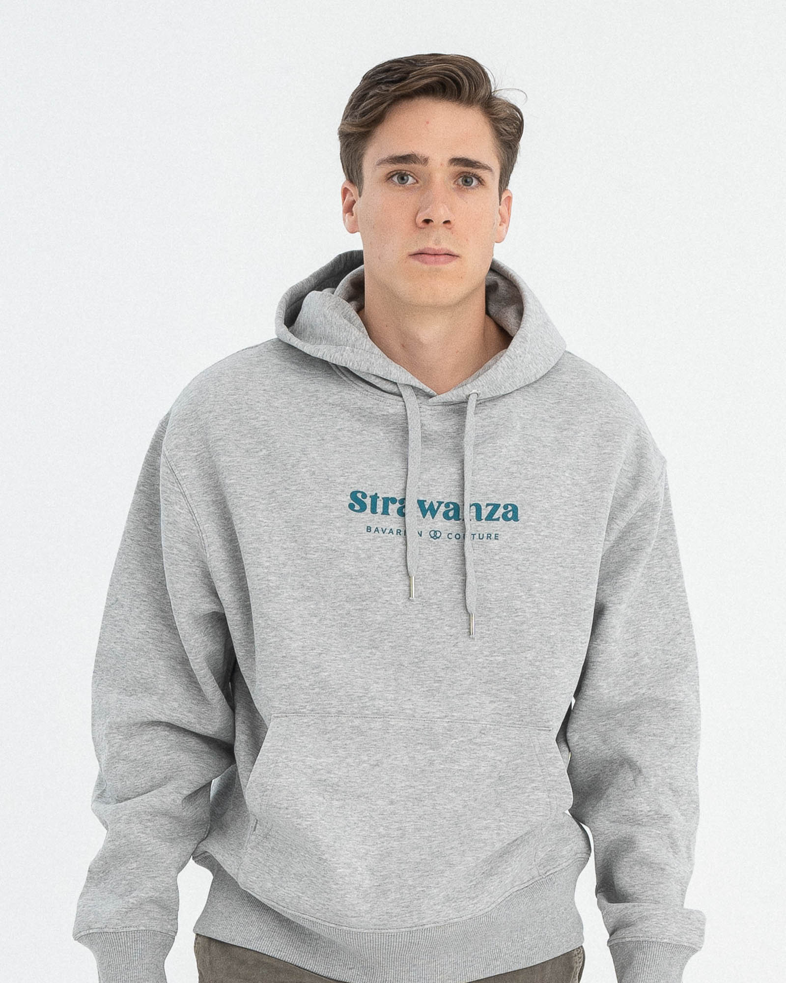 Ein männliches Model trägt einen grauen Hoodie und auf der Vorderseite, auf Höhe der Brust sind zwei in petrolgrüne "Strawanza" und "BAVARIAN COUTURE" Schriftzüge abgebildet. 