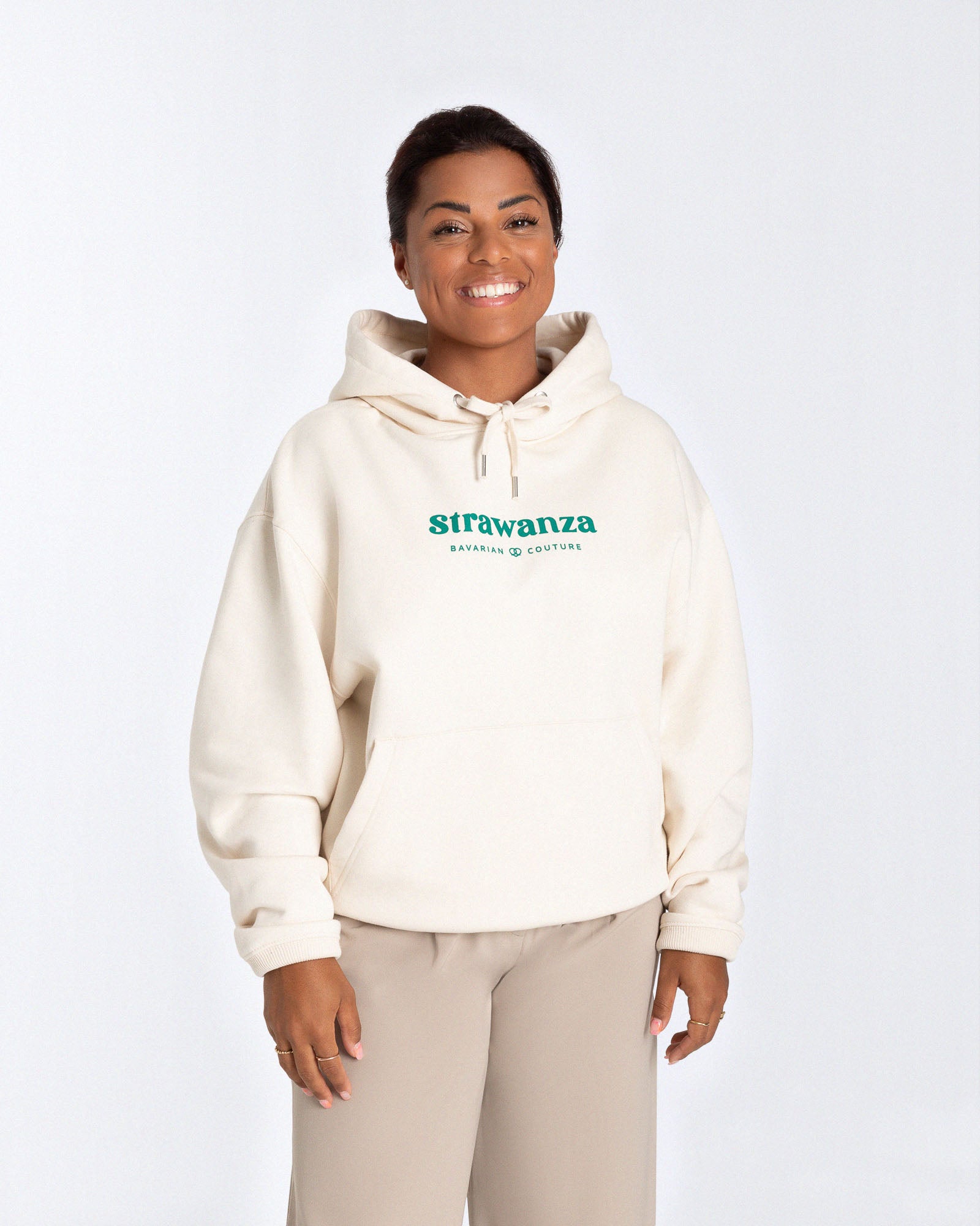 Ein weibliches Model trägt einen Hoodie in der Farbe Natur, welches einen "Strawanza" Schriftzug in der Farbe dunkelgrün auf der Brust hat als Motiv.