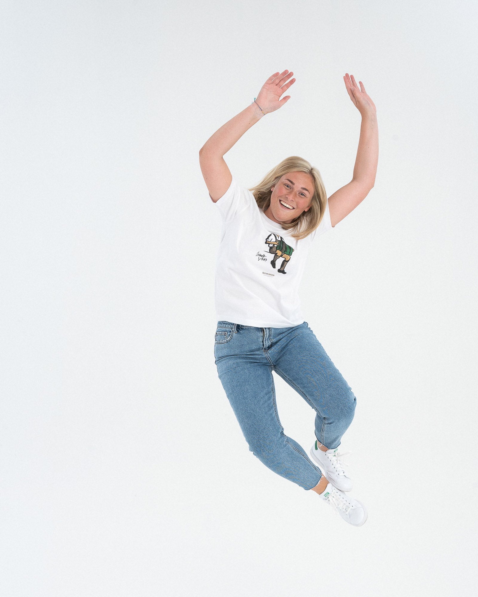 Ein weibliches Model trägt ein weißes T-Shirt mit einem Mann in Tracht sitzend, der Akkordeon spielt als Vordermotiv auf der Brust.