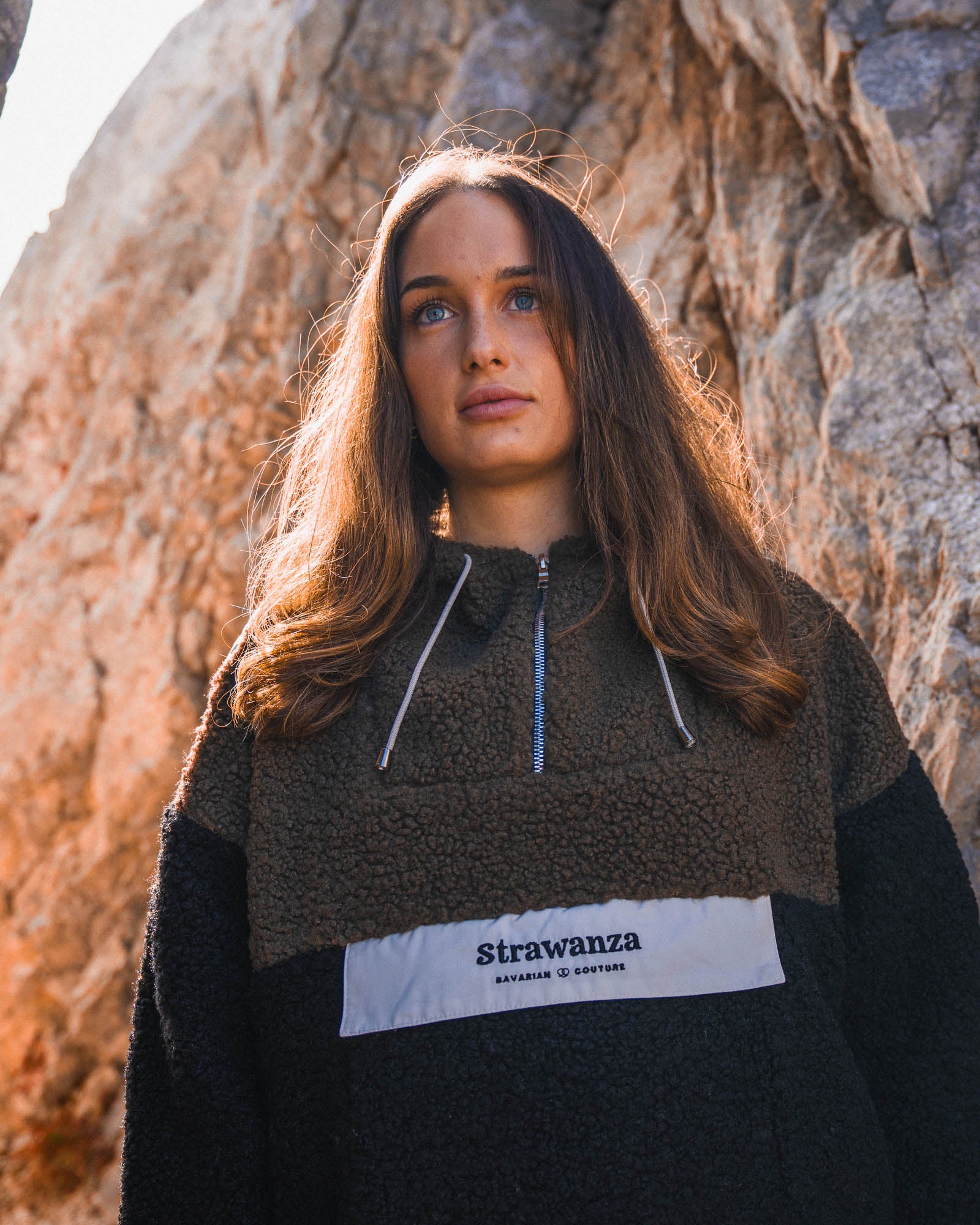 Entdecken Sie den stylischen 'SHERPA ANORAK DARK' von Strawanza, ideal für Outdoor-Abenteuer. Das Model präsentiert diese trendige Anorak Jacke in einer natürlichen Kulisse, die Funktionalität und Modebewusstsein vereint. Die Jacke zeichnet sich durch ihren dunkelgrünen Sherpa-Fleece an der Oberseite und den schwarzen Unterteil aus, ergänzt durch das charakteristische weiße Strawanza Logo auf der Brust. Dieses Must-have der Outerwear-Kollektion bietet Komfort und Stil für die kälteren Tage