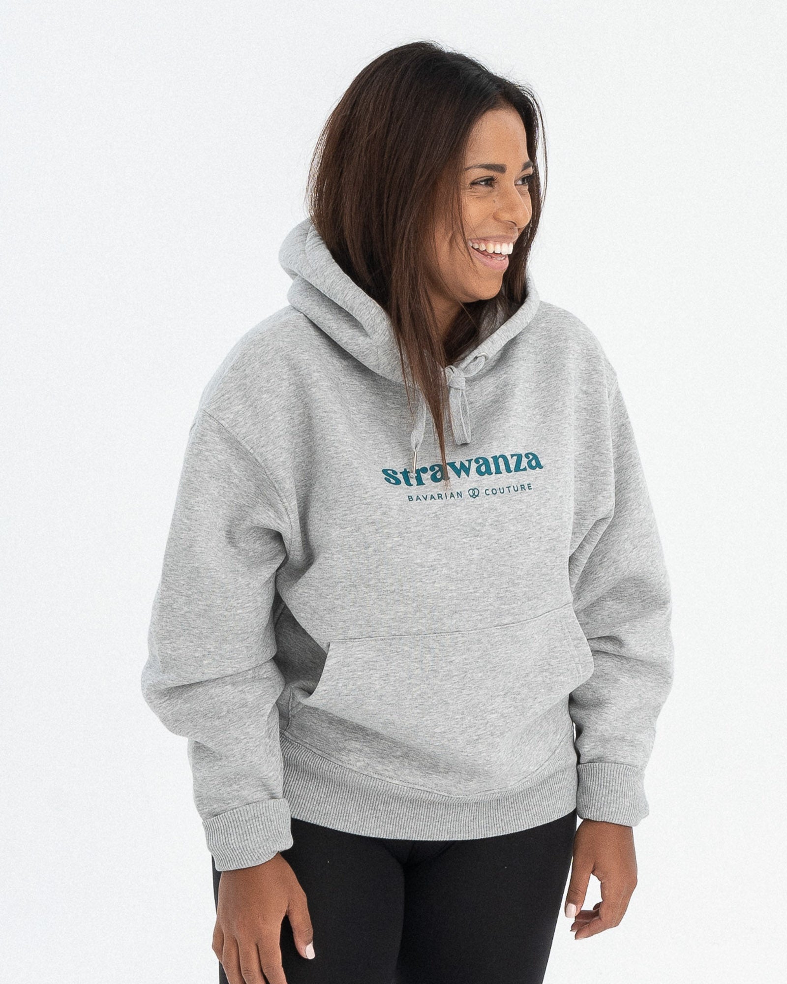 Ein weibliches Model trägt einen grauen Hoodie, wo ebenfalls zwei petrolgrüne "Strawanza" und "BAVARIAN COUTURE" Schriftzüge vorhanden snd.