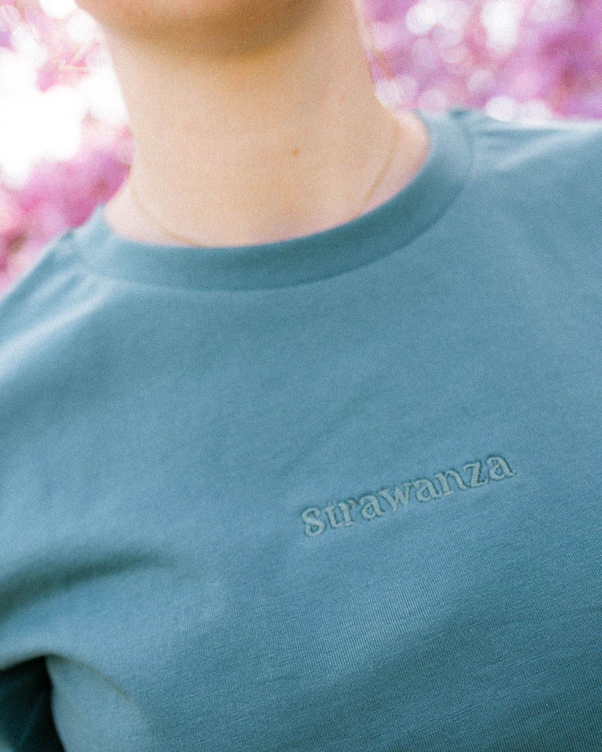 Ein grünes T-Shirt mit einem Ton in Ton "Strawanza" Schriftzug vorne auf der Brust. 